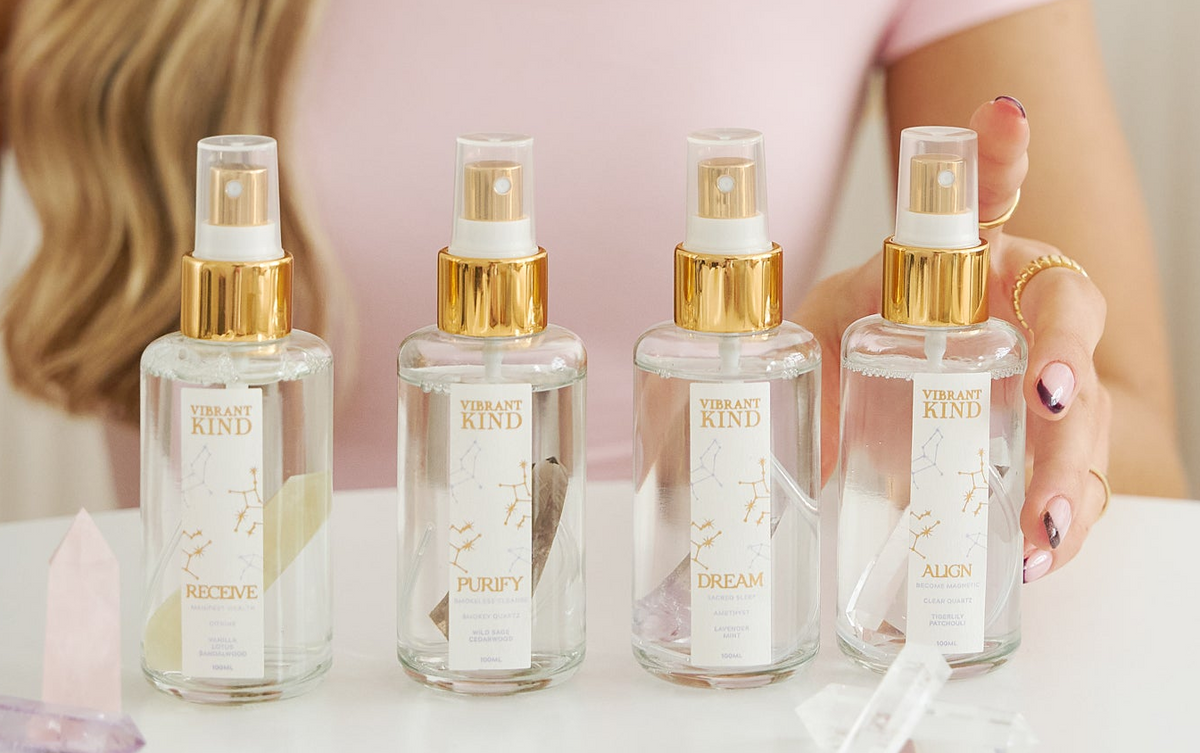 Four perfume bottles with gold caps on a white surface, held by a person.